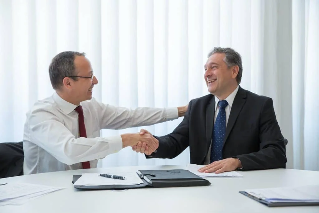 Lawyer shaking hands with a client across a desk
